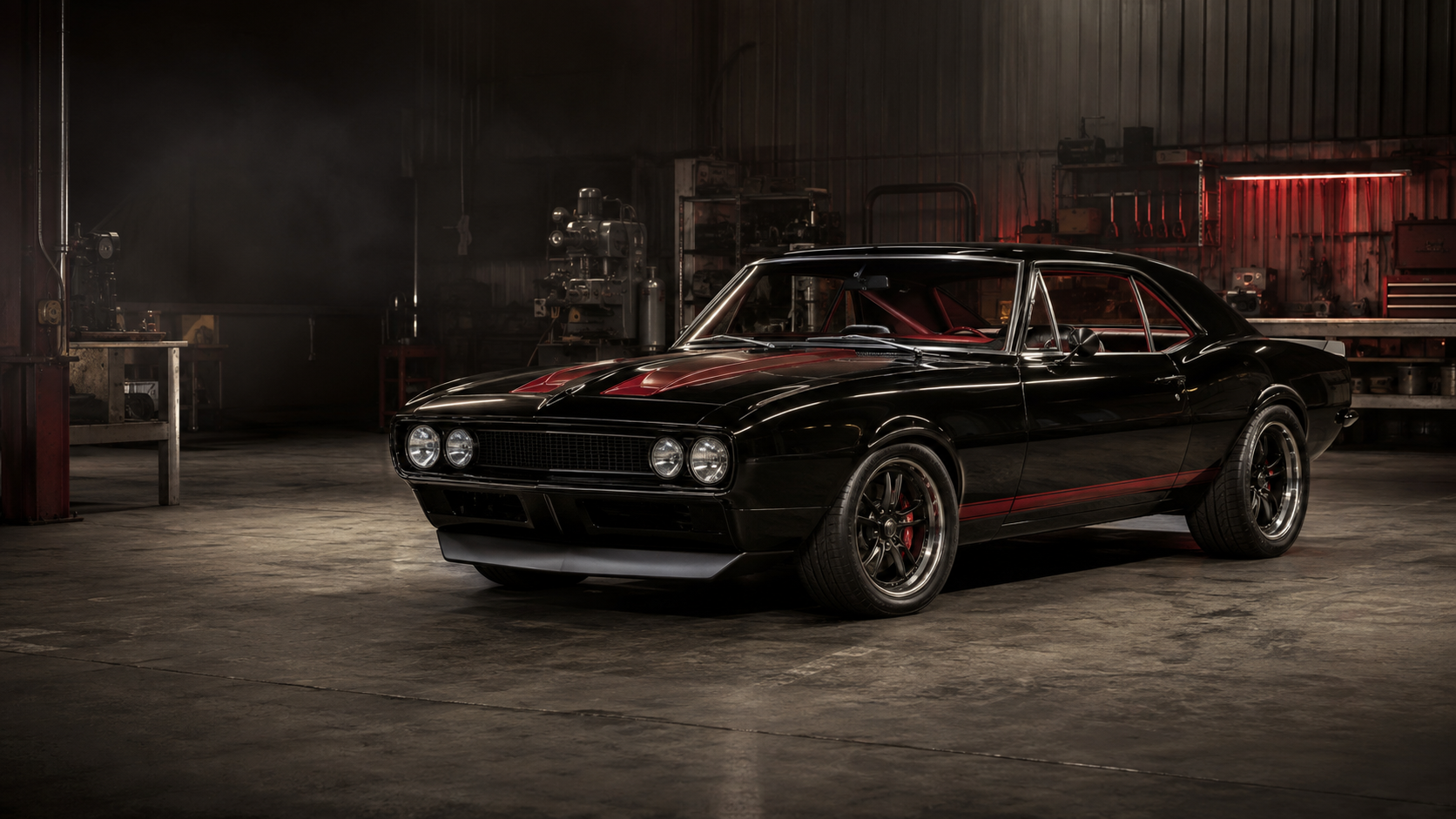 A black classic muscle car inside a restoration and performance workshop